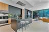 Contemporary kitchen featuring flat-panel cabinetry, a central island with a waterfall edge, stainless steel built-in double wall ovens, ceiling-integ
