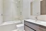 Floating dual-drawer vanity with white countertop, undermount sink, rainfall shower system, glass panel enclosure, and wall-mounted mirror