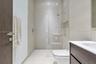Walk-in shower with a glass enclosure, rain-style shower head, and recessed wall niche
