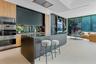 Contemporary kitchen featuring matte cabinetry, wood-finish paneling, a large island with a surface-mounted cooktop, floor-to-ceiling glass sliding do