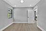 Neutral-toned interior room featuring wood-finish flooring, recessed lighting, a globe flush-mount fixture, a window with a black frame, and a solid-c