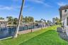 Waterfront property featuring a private dock, bulkhead, and manicured lawn