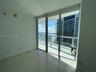 Floor-to-ceiling sliding glass doors, private balcony with metal railing, and large-format tile flooring