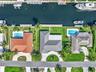 Waterfront property featuring a private boat dock, rectangular swimming pool, manicured lawn, and multi-faceted hipped roofline