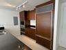 Kitchen featuring custom wood-finish cabinetry, integrated panel-ready refrigerator, stainless steel built-in wall oven and microwave, dark stone coun