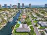 Aerial perspective of a waterfront property featuring direct canal access, a private swimming pool, concrete hardscaping, and mature tropical landscap