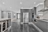 Modern kitchen featuring handleless cabinetry, stainless steel appliances, a built-in wine refrigerator, under-cabinet lighting, and a stone-patterned