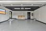 Garage featuring a speckled epoxy floor coating, contrasting black ceiling, dual flush-mount LED lighting, and an elevated entryway threshold