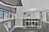 Wet bar featuring integrated stainless steel under-counter wine refrigerators, solid-surface countertops, recessed lighting, and large-format floor ti