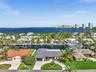 Waterfront property featuring a private boat dock, concrete seawall, circular driveway, and mature landscaping