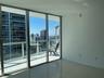 Floor-to-ceiling glass walls, polished tile flooring, and a private balcony with metal railings and a glass surround