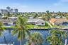 Waterfront property featuring a private seawall, manicured lawn, concrete paver walkway, and mature landscaping