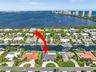 Aerial perspective of a canalfront property featuring a private boat dock, multi-pitched roofline, curved paved driveway, and mature landscaping