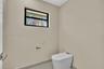 High-profile window with black frame, wall-mounted toilet, and sleek metal toilet paper holder