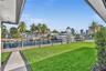 Waterfront grounds featuring a private dock, bulkhead, expansive lawn, and concrete pathway