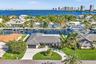 Waterfront single-story residence featuring a tile roof, concrete circular driveway, manicured lawn, and mature palm trees