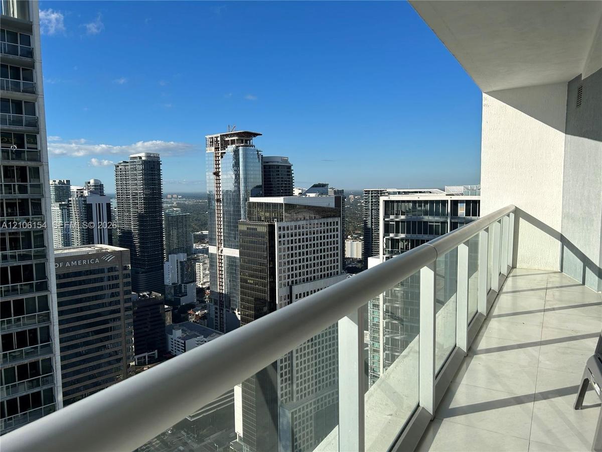 Private balcony featuring a glass-panel railing, metal handrail, and oversized tile flooring