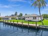 Waterfront exterior featuring a private dock, manicured lawn, and exterior lighting