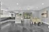 Open-concept kitchen featuring two-toned flat-panel cabinetry, a stone-surface waterfall island, recessed lighting, and sliding glass doors