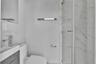 Modern bathroom featuring a wood-finish vanity, rectangular vessel sink with a polished chrome faucet, glass-enclosed shower with tiled walls, and pol