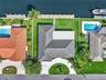 Waterfront property featuring a private dock, expansive lawn, tile roof, and a circular driveway