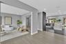 Open-concept floor plan featuring wood-finish flooring, recessed lighting, a stone-surfaced kitchen island, and a dark-toned accent pillar