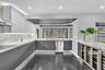 Kitchen featuring flat-panel cabinetry, light-toned stone-finish backsplash, built-in stainless steel appliances, polished flooring, and dual glass-do
