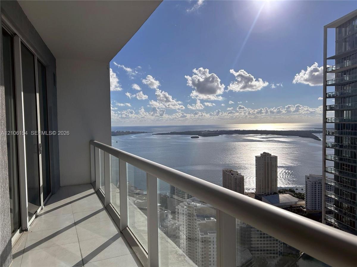 Private covered balcony with tile flooring and a glass panel railing