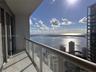 Private covered balcony with tile flooring and a glass panel railing