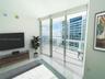 Floor-to-ceiling glass sliding doors opening to an expansive balcony, polished tile flooring, and integrated motorized window shades