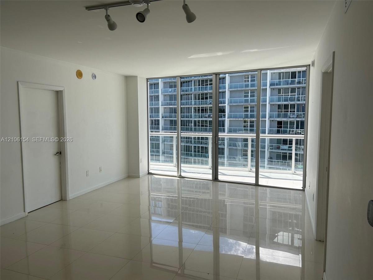 Floor-to-ceiling glass windows, polished tile flooring, and multi-directional track lighting