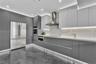 Kitchen featuring floor-to-ceiling cabinetry, stainless steel appliances, stone-surface backsplash, integrated under-cabinet lighting, and polished co