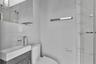 Modern bathroom featuring a wood-finish vanity, white rectangular vessel sink, polished chrome fixtures, wall-mounted mirror, and walk-in shower with 