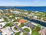 Aerial perspective of a waterfront property featuring a tile roof, paved circular driveway, landscaped lawn, and a private swimming pool