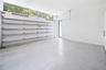 Garage space featuring speckled epoxy flooring, white paneled walls, a ceiling-mounted automatic door opener, and a row of horizontal transom windows