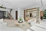 Open floor plan featuring a floating staircase with metal railings, built-in floor-to-ceiling cabinetry with glass display shelving, recessed ceiling 
