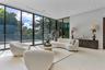 Floor-to-ceiling glass wall panels with dark metal framing, expansive polished tile flooring, and recessed ceiling lighting