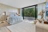 Floor-to-ceiling sliding glass doors opening to a balcony, light-toned wood-finish flooring, recessed ceiling lighting, and patterned wallpaper featur