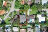 Aerial view of a residential property featuring a hipped roof, paved driveway, swimming pool, and established perimeter landscaping
