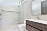 Modern floating vanity featuring wood-finish cabinetry, white countertop, integrated sink, and rectangular wall mirror