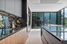 Modern kitchen featuring matte cabinetry, wood-finish lower cabinetry, integrated dark stone-surface countertops, floor-to-ceiling glass panel walls, 