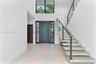 Grand foyer featuring a double-height ceiling, floor-to-ceiling windows, modern floating staircase with cable railing, large-format tile flooring, and