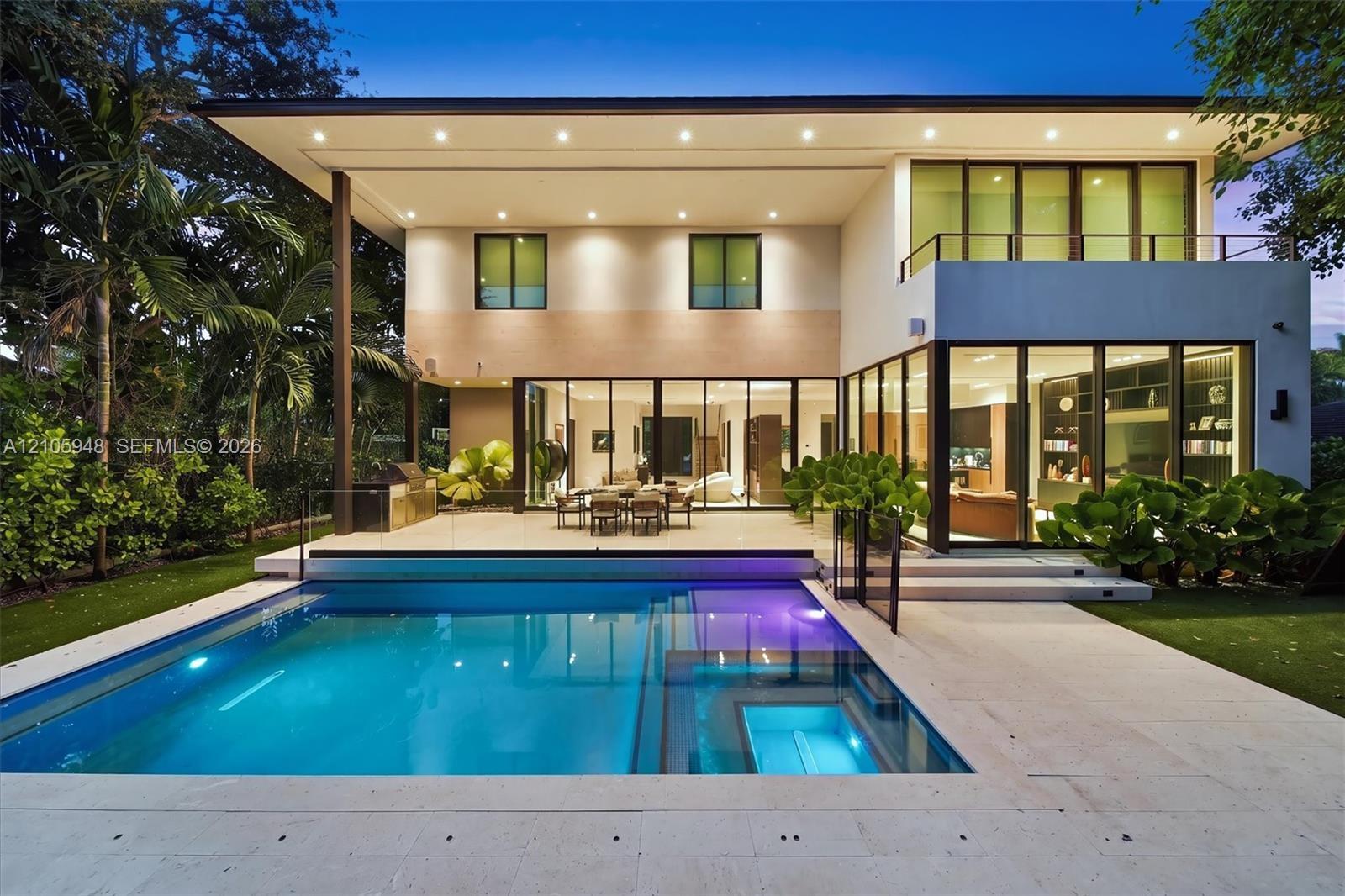 Modern two-story exterior featuring floor-to-ceiling glass sliding doors, a flat roofline, an integrated swimming pool with a stone patio surround, an