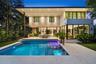 Modern two-story exterior featuring floor-to-ceiling glass sliding doors, a flat roofline, an integrated swimming pool with a stone patio surround, an