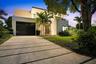 Contemporary exterior featuring smooth stucco siding, a multi-level balcony with a metal railing, a paved driveway with integrated linear landscaping,