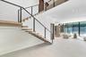 Floating staircase with wood-finish treads and horizontal cable railing, large-format tile flooring, and expansive floor-to-ceiling glass wall panels