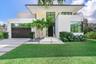 Modern architectural exterior featuring smooth stucco finish, geometric flat roofline, oversized floor-to-ceiling windows, second-story balcony with m