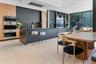 Contemporary kitchen featuring matte dark cabinetry, wood-finish cabinetry accents, a large center island, floor-to-ceiling glass walls, and integrate