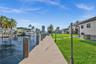 Waterfront property featuring a private bulkhead dock, manicured lawn, stone paver pathway, and nautical piling hardware