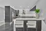 Modern kitchen featuring dual-tone cabinetry, quartz countertops, stainless steel appliances, an island with slatted detailing, and under-cabinet ligh